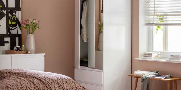 Pink bedroom with white mirrored wardrobe and clothing.